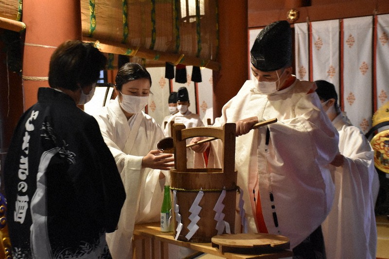 宮司から「霊水」を分け与えられる醸造業者(左)=栃木県日光市の日光二荒山神社で2021年10月12日、渡辺佳奈子撮影