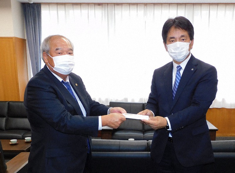 富山南ライオンズクラブの林孝会長(左)から寄付金を受け取る白江日呂雄・県NIE推進協議会長=富山県高岡市の市立志貴野中学校で、大森顕浩撮影
