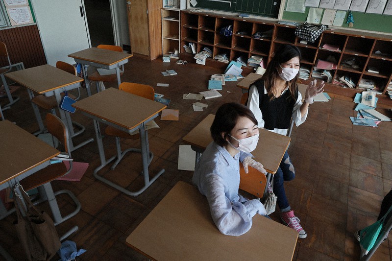 教室を友人と訪れ、自分の席に座る当時2年生だった輪島あゆみさん(手前)=福島県大熊町で2021年10月15日、和田大典撮影