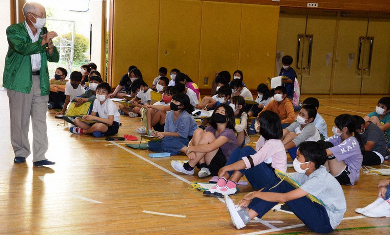 「玉川上水の自然保護を考える会」の萩本悦久さん(左)の話を真剣な表情で聞く立川市立新生小学校の5年生たち=立川市で
