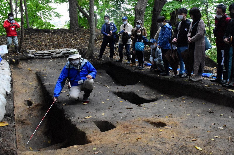 三内丸山遺跡で見つかった溝状遺構について解説する同遺跡センター職員(左)=青森市の同遺跡で2021年10月16日、平家勇大撮影