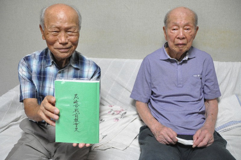 製本された「尼崎市戦前教育史」を手にする池田洋さん(左)と末方鉄郎さん=兵庫県西宮市で2021年9月22日午後2時31分、中村清雅撮影