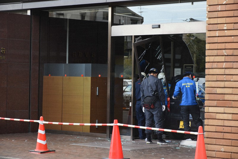 軽乗用車がドアガラスを破って突っ込み、佐賀県警の捜査員が現場を調べている佐賀銀行本店=佐賀市唐人2の佐賀銀行本店で2021年10月18日午後2時50分、高橋広之撮影