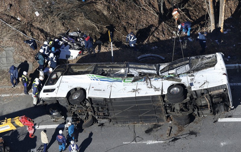 クレーン車で移動されたスキーバスと現場の散乱物を調べる長野県警の捜査員ら=長野県軽井沢町で2016年1月15日、本社ヘリから