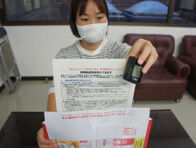 パルスオキシメーターと一緒に特例郵便等投票の制度を知らせるチラシを入れる糸島保健福祉事務所の職員=福岡県糸島市で2021年10月14日午後4時39分、蓬田正志撮影