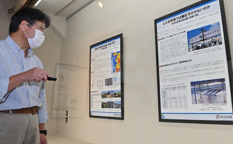 2019年台風19号による被害を伝えるパネルを指す佐藤公館長=福島県北塩原村桧原の磐梯山噴火記念館で2021年9月26日、三浦研吾撮影