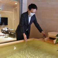 客室に併設されたヒノキ風呂の湯加減をチェックする内田宗一郎社長＝静岡県熱海市東海岸町で2021年10月9日、太田圭介撮影
