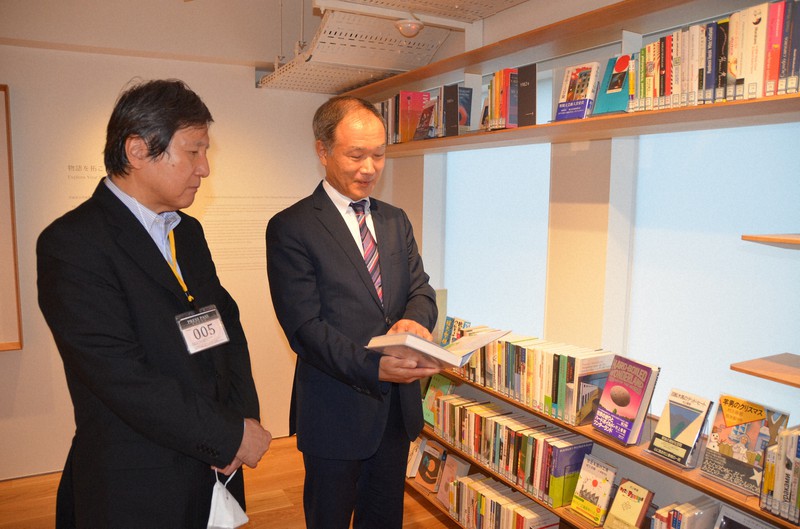 村上春樹の本を手にする十重田裕一さん(右)と重里徹也さん=村上春樹ライブラリーで2021年10月5日撮影