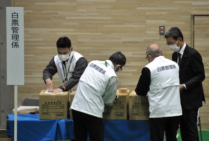 甲賀市議選で市選管委員長（右端）の確認を受けながら、未使用の票を封印する白票管理係＝甲賀市水口町鹿深の水口体育館で2021年10月17日午後9時9分、村瀬優子撮影