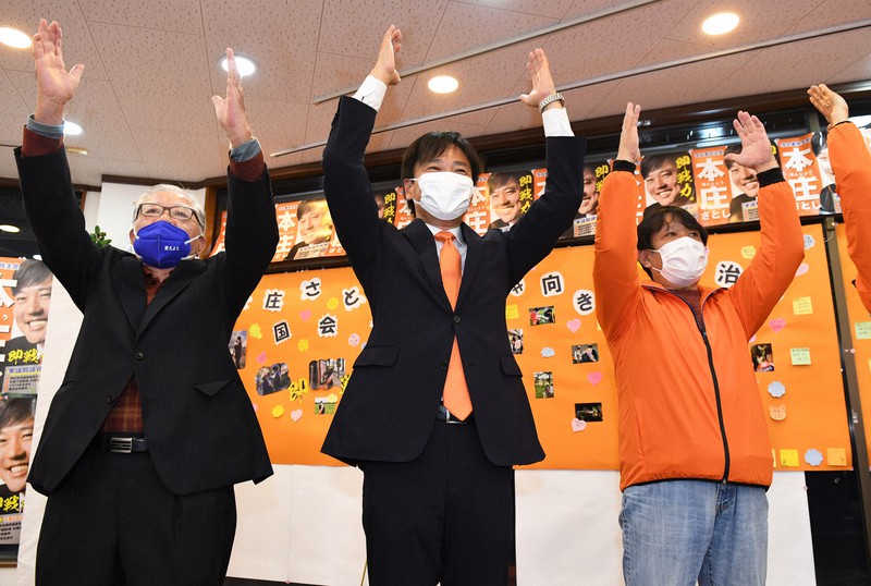 当選確実となり、万歳をして喜ぶ本庄知史氏(中央)=千葉県柏市で2021年10月31日午後8時31分、大西岳彦撮影