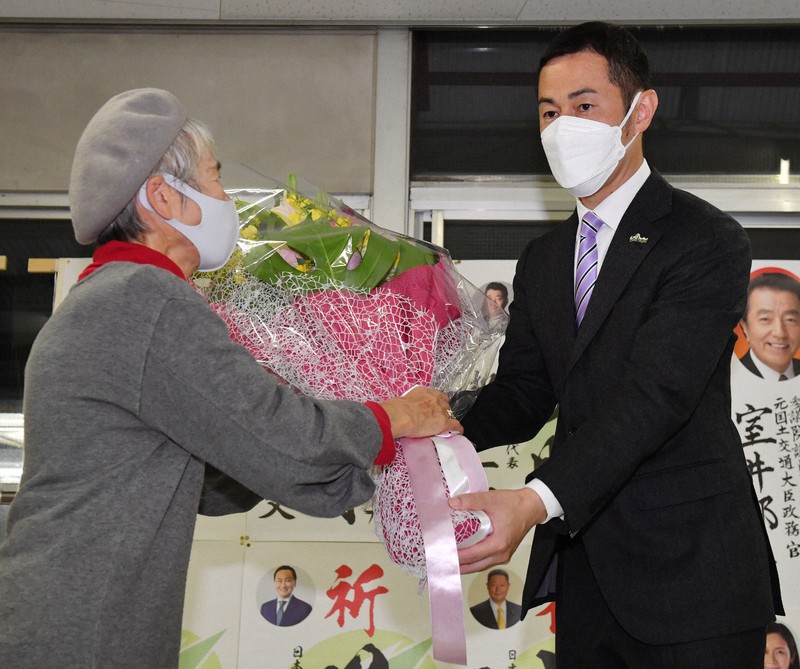 当選確実となり、花束を受け取る漆間譲司氏(右)=大阪府豊中市で2021年10月31日午後9時29分、木葉健二撮影