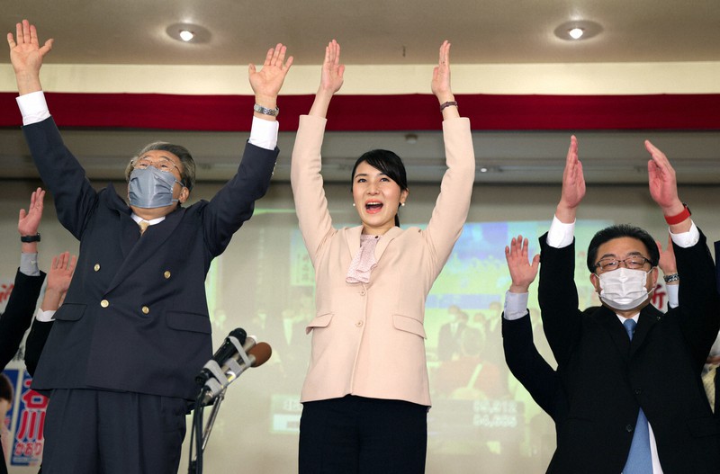 当選確実の一報に、万歳して喜ぶ石川香織氏(中央)=北海道帯広市で2021年10月31日午後11時39分、貝塚太一撮影