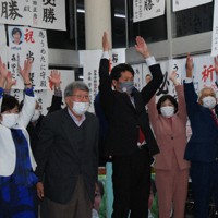 当選確実の報を受け万歳する立憲の梅谷守氏（中央）。自民候補と130票差での勝利だった＝新潟県上越市で2021年11月1日午前0時10分ごろ、内藤陽撮影