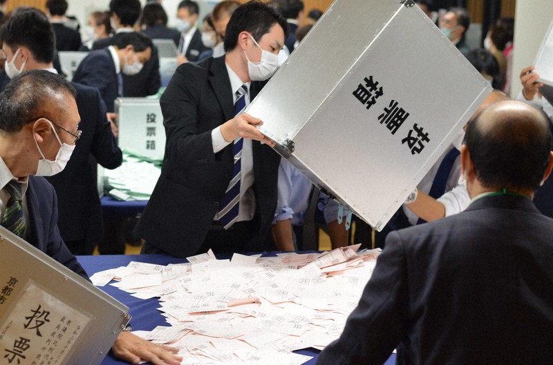 開票作業をする京都市職員ら。比例近畿ブロックで多数の「民主党」票が府内で投票された=上京区役所で2021年10月31日午後9時29分、藤河匠撮影