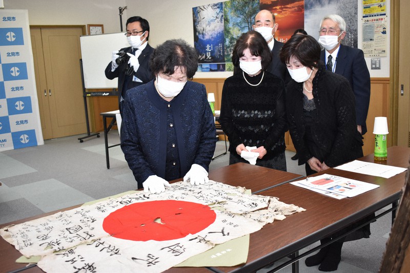 兄の名が書かれた日の丸を感無量の表情で見つめる中股かず子さん(左)ら妹たち=北見市で2021年11月6日午後1時24分、本多竹志撮影