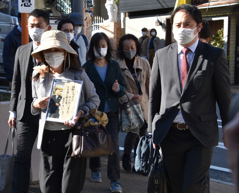 告訴状を提出するため、遺影を掲げながら静岡県警熱海署に入る遺族らと弁護団長の加藤博太郎弁護士(右端)=静岡県熱海市で2021年11月10日午後0時58分、深野麟之介撮影