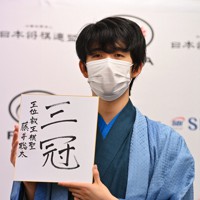 史上最年少での3冠を達成し、「三冠」と自筆した色紙を掲げる藤井聡太新叡王＝東京都渋谷区で2021年9月13日午後7時57分、大西岳彦撮影