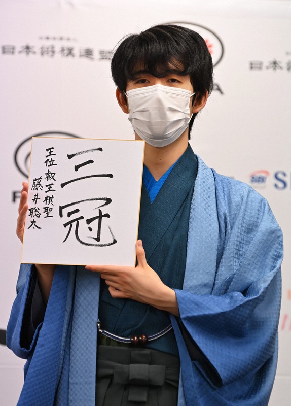 史上最年少での3冠を達成し、「三冠」と自筆した色紙を掲げる藤井聡太新叡王＝東京都渋谷区で2021年9月13日午後7時57分、大西岳彦撮影