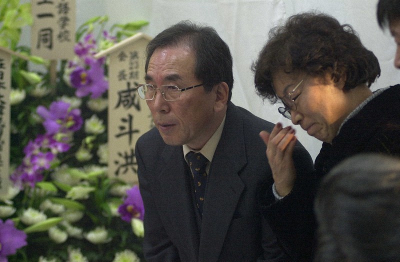 故・李秀賢さんの通夜で焼香に訪れた参列者に頭を下げる父・盛大さんと涙をぬぐう母・辛潤賛さん=東京都荒川区東日暮里で2001年1月28日午後6時40分、森田剛史撮影