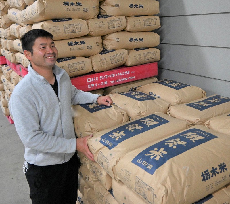 出荷を待つ「山田錦」の前に立つ海老原さん=栃木県下野市の山田錦栽培研究所で2021年11月9日、御園生枝里撮影