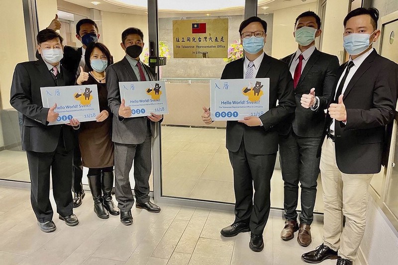 「駐リトアニア台湾代表処」のプレートの前でポーズを取る職員ら=18日、台湾外交部提供・AP
