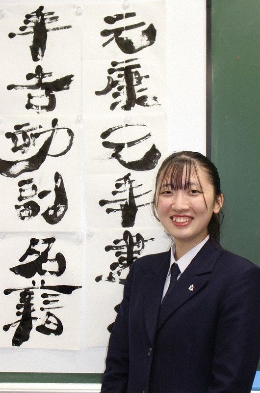 準大賞受賞作と同じ文字を書いた作品の前に立つ鳥取東3年の平井耶衣さん