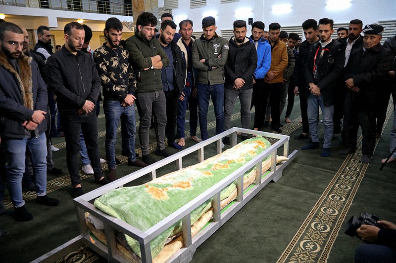 ベラルーシとポーランドの国境地帯で亡くなった知人の遺体を囲むクルド人ら=イラク・アルビルで2021年11月15日、AP