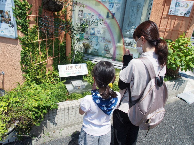 「昆虫天国」の前で手を合わせる親子=アビーコム提供