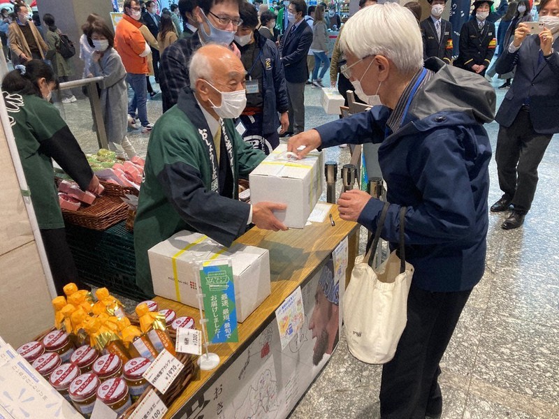 JR上野駅で「秋の味覚セット」を予約客に手渡す中川勝・山形県米沢市長(手前左)=JR東日本提供
