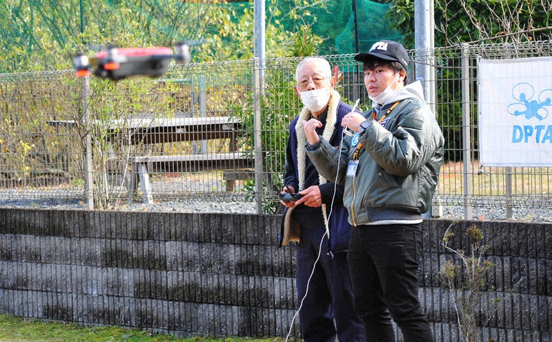 インストラクター(右)の指示通りにドローンを操縦する田中衛さん=京都府福知山市大内で2021年12月10日午前10時53分、佐藤孝治撮影