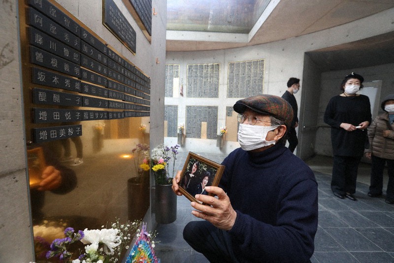 震災で犠牲になった母と姉の写真とともに銘板を眺める増田潤さん=神戸市中央区で(代表撮影)