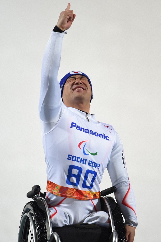 ソチ冬季パラリンピック・アルペンスキー男子回転座位で優勝しフラワーセレモニーで右手を突き上げる鈴木猛史=ロシア・ソチのロザフータル・センターで2014年3月13日、宮間俊樹撮影