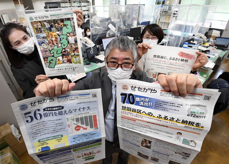 ふるさと納税の影響で区民税が他の自治体に流出している実情を伝える区報を手にする、東京都世田谷区の高井浩幸課長(中央)ら経営改革・官民連携担当課の職員=世田谷区役所で2021年12月17日、竹内紀臣撮影