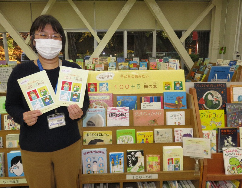 「大人も一緒に楽しめる105冊です」と「100+5冊の本」コーナーで話す司書の桑名裕子さん=大阪府吹田市出口町の同市立中央図書館内で2021年12月9日午後4時19分、三角真理撮影