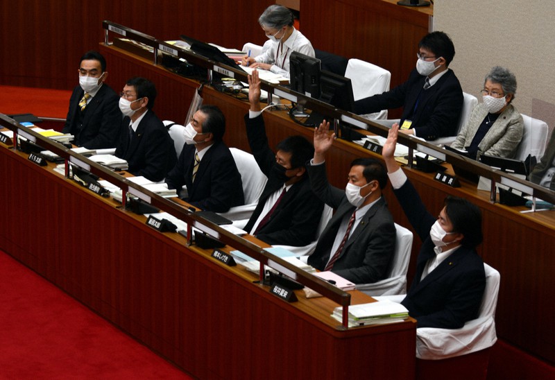 住民投票条例案が審議された市議会総務委員会の採決では、市議6人(前列)の賛否が真っ二つに割れ、委員長裁決で可決された。挙手しているのは賛成する市議=東京都武蔵野市で2021年12月13日午後8時28分、李英浩撮影