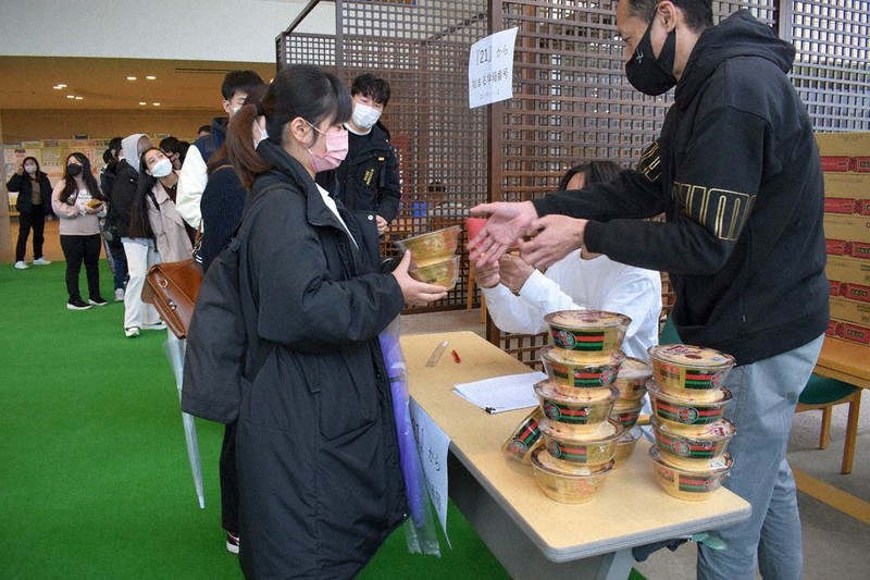 一蘭から寄贈されたカップ麺を受け取る学生(左)