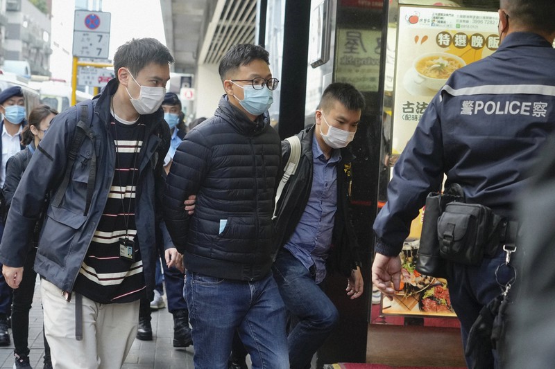 「立場新聞」の幹部(左から2人目)を逮捕し、連行する警察官ら=香港で2021年12月29日、AP
