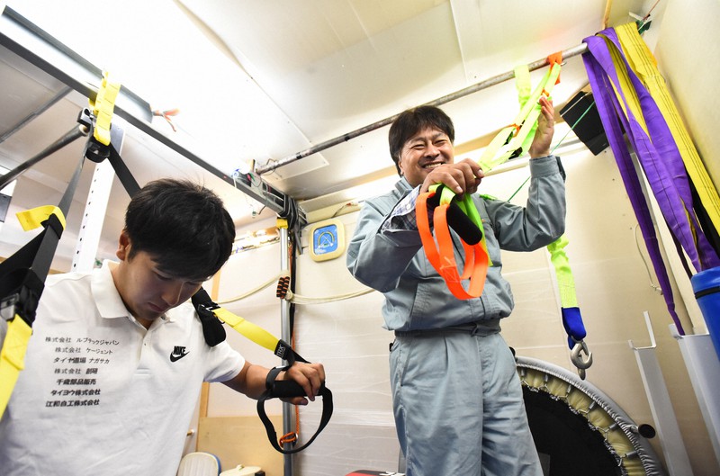 スピードスケート男子の村上右磨(左)のために車庫を改装して作ったトレーニング室で、自作のトレーニング用具を手に笑顔を見せる父忠則さん=北海道帯広市で2017年7月20日、宮間俊樹撮影