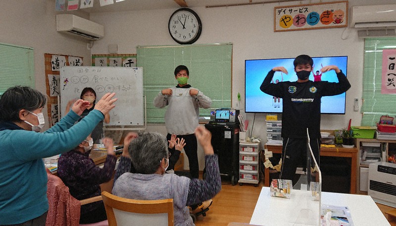 大掃除を手伝う合間、お年寄りと一緒に体操するセガサミー野球部の選手=八王子市川口町の「デイサービスやわらぎ」で