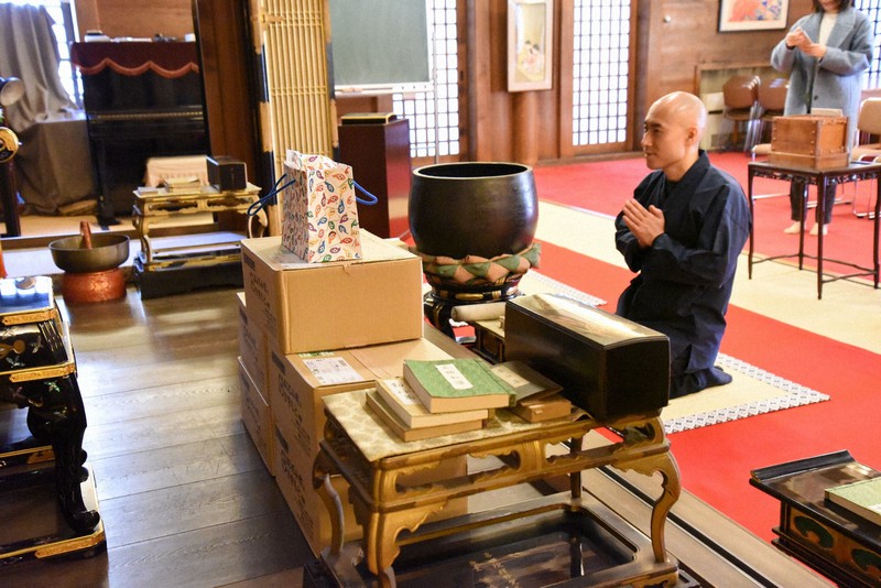 お寺のご本尊に手を合わせる松本紹圭さん=2019年、東京都港区で筆者撮影