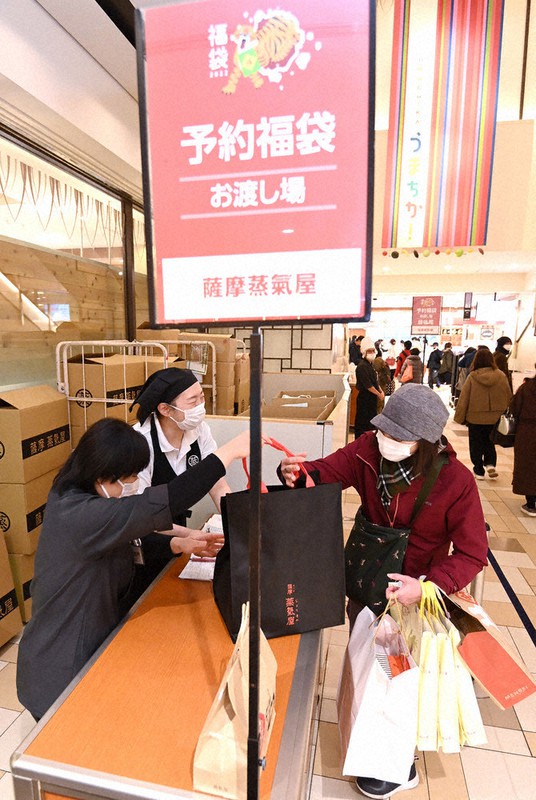 密を避けるため事前予約で販売された福袋を受け取る女性=福岡市博多区の博多阪急で2022年1月2日午前9時33分、徳野仁子撮影