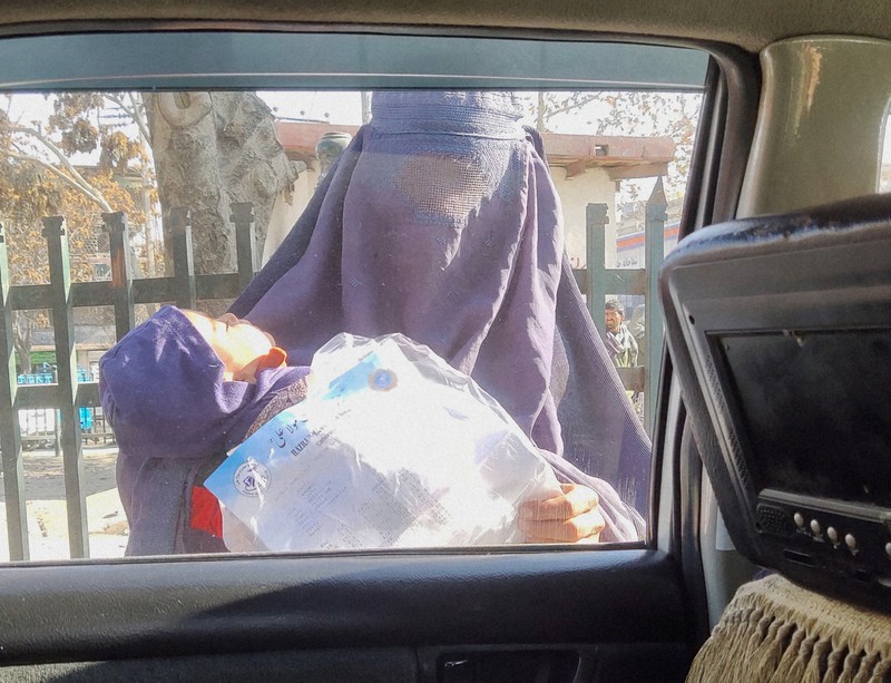 子供を抱いた物乞いの女性。病気の子の治療費を求めていた=アフガニスタンの首都カブールで2021年12月初旬、松井聡撮影