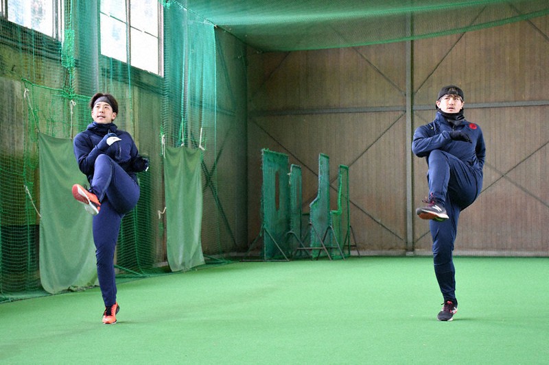 室内練習場でウオーミングアップを行う鈴木選手(左)と小田選手=宿毛市大深浦の市野球場で、上野力撮影