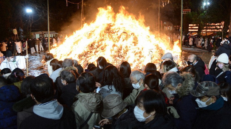 燃え上がる御神火を囲み、無病息災を祈る参拝客ら=仙台市青葉区の大崎八幡宮で2022年1月14日、深津誠撮影