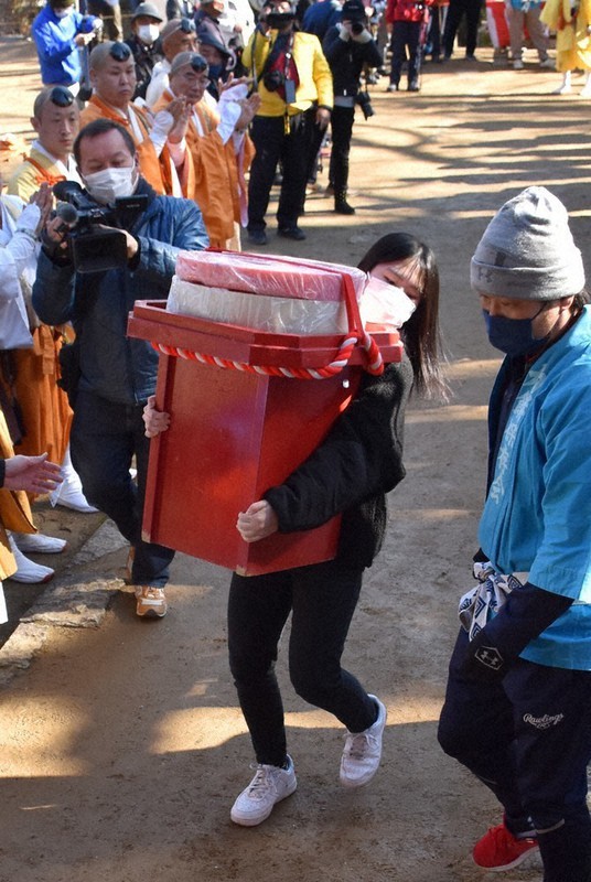 巨大な鏡餅を抱えて本堂前に運ぶ代表者=徳島県上板町新宅の大山寺で、国本ようこ撮影