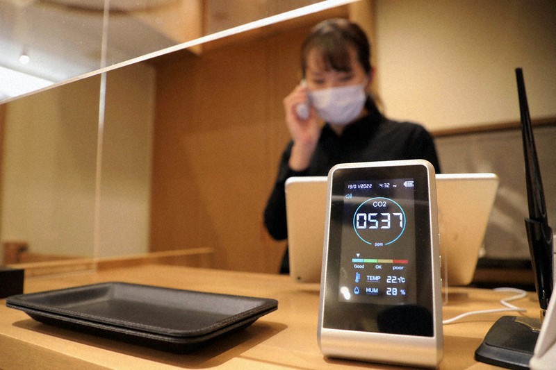 開店前、二酸化炭素濃度の計測機器が置かれる会計で、予約キャンセルの電話を受ける「和食日和おさけと日本橋」の従業員=東京都中央区で19日、宮武祐希撮影