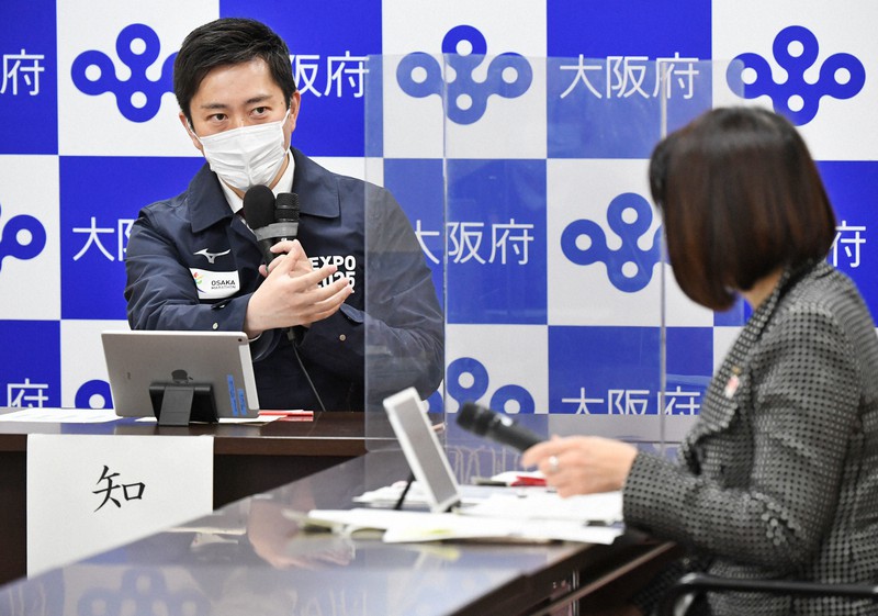 大阪府の新型コロナウイルス対策本部会議で、藤井睦子健康医療部長(右)と話す吉村洋文知事=大阪市中央区で2022年1月21日午後2時15分、山崎一輝撮影