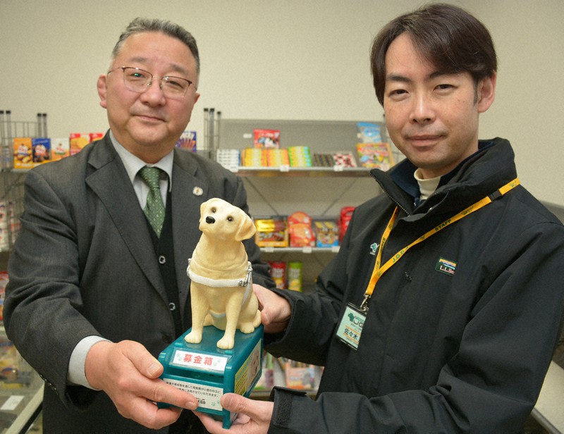 島根あさひ社会復帰促進センターの売店に置かれた募金箱を持つ平床隆二センター長(左)と日本盲導犬協会島根あさひ訓練センターの佐々木重紀センター長=浜田市で2022年1月20日午後3時5分、萱原健一撮影