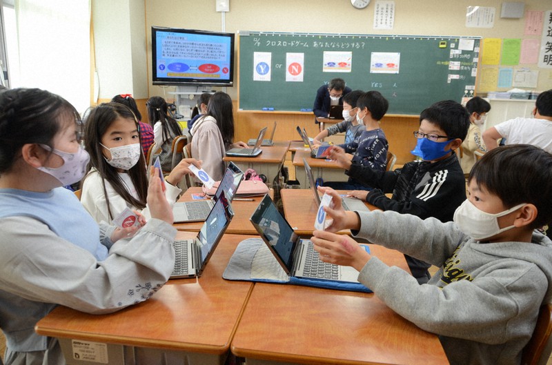 「Yes」「No」のカードを挙げて新型コロナウイルスへの対応を話し合う児童たち=兵庫県西宮市立夙川小で2021年12月8日午前11時30分、井上元宏撮影