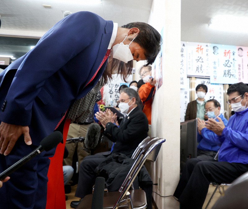 支持者の前で頭を下げる岸本洋平氏(左)=沖縄県名護市で2022年1月23日午後10時36分、喜屋武真之介撮影